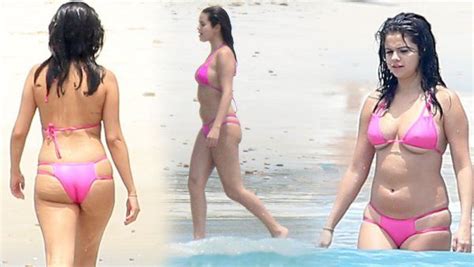 two women in pink bikinis are walking on the beach and one is wearing black hair