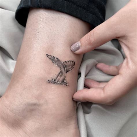 Micro-realistic whale tail tattoo on the ankle.