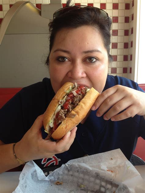 a woman eating a hot dog with toppings on it at a table in a restaurant