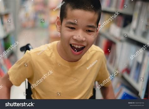 Disabled child on wheelchair having fun choosing books from shelves ...