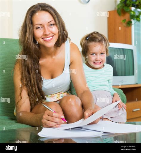 Cheerful woman and girl signing application form for kindergarten indoor. Focus on woman Stock ...