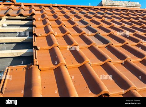 Overlapping rows of yellow ceramic roofing tiles mounted on wooden ...