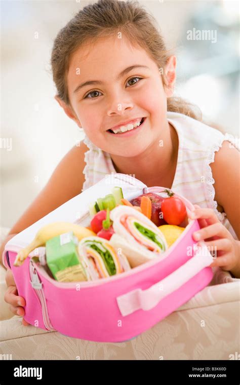 Young girl holding packed lunch in living room smiling Stock Photo - Alamy