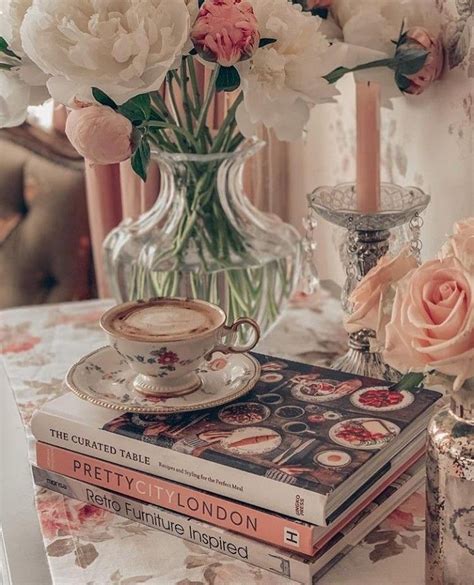 a table topped with books and flowers next to a vase filled with pink ...