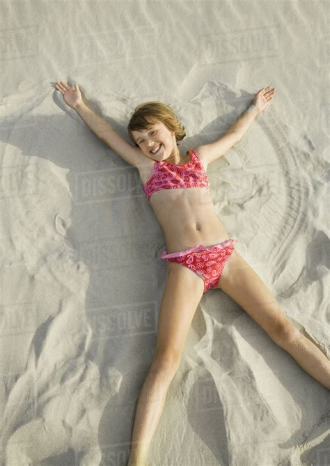 Girl making angel in sand on beach, high angle view - Stock Photo ...