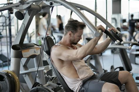 Muscular man exercising with shoulder press machine in gym · Free Stock Photo