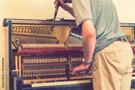 Piano tuning process. closeup of hand and tools of tuner working on grand piano. Detailed view ...