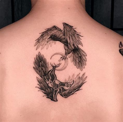 the back of a woman's neck with a bird and flower tattoo on it