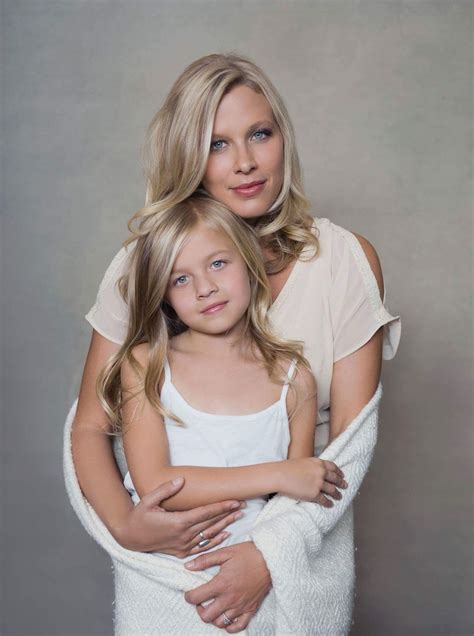 a mother and daughter hugging each other in front of a gray background ...