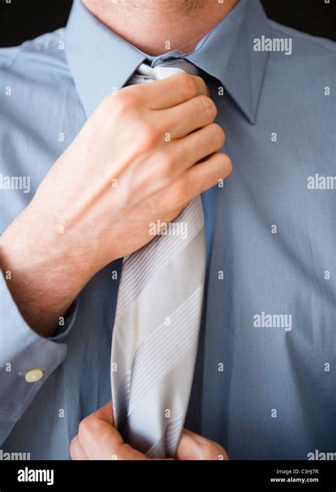 Businessman adjusting tie Stock Photo - Alamy