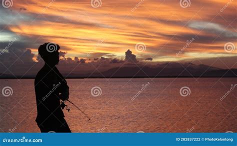 Silhouette of a Fisherman with a Fishing Rod in the Lake at Sunset ...