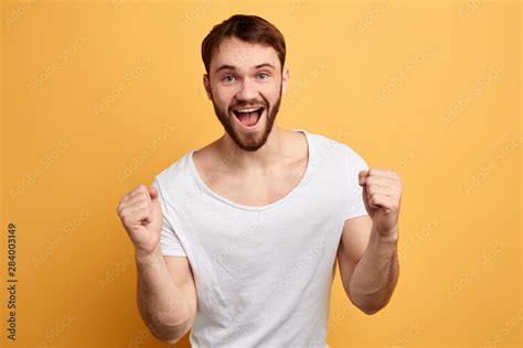 satisfied positive bearded young man celebrating success isolated over ...
