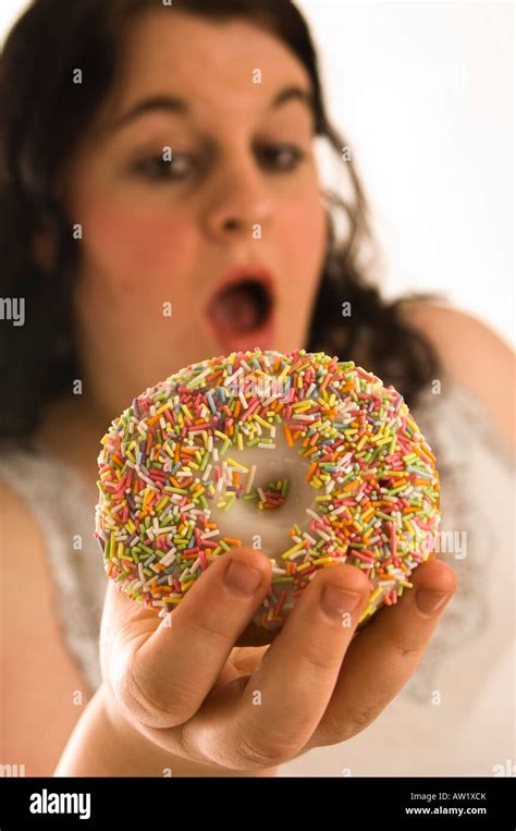 fat overweight young woman guiltily eating  sweet donut stock photo
