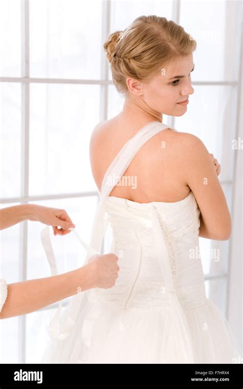 Beautiful bride putting on her white wedding dress Stock Photo - Alamy