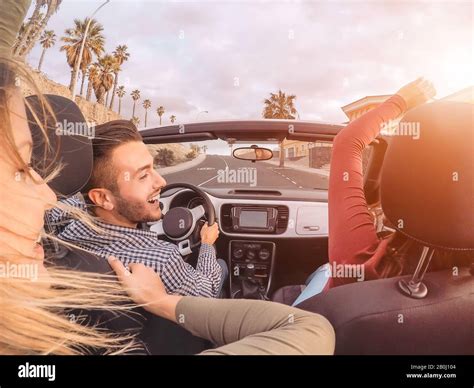 Happy friends having fun on convertible car during road trip - Group ...