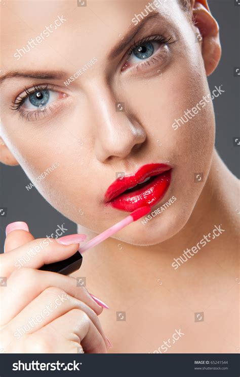 portrait  young woman applying lip gloss stock photo
