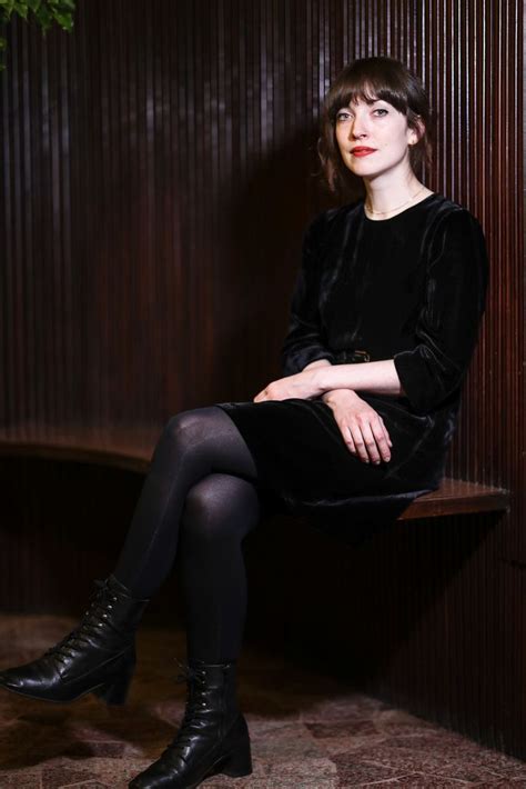 a woman sitting on top of a wooden bench wearing black stockings and ...