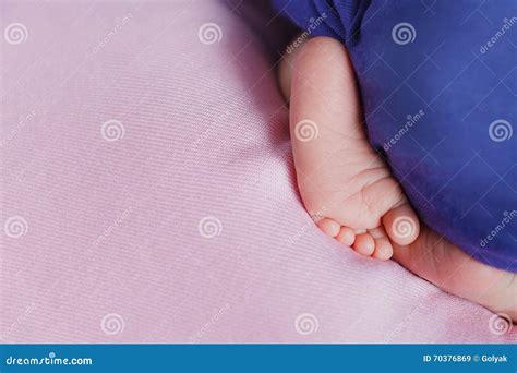 Маленькие ноги Newborn младенец смотря вне из-под одеяла Стоковое ...