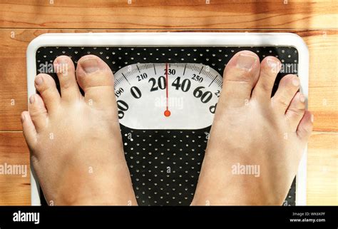 Feet of a fat person on a weight scale (measuring both in pounds and ...