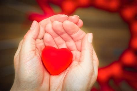 Premium Photo | A heart in hands on valentine's day on a wooden ...