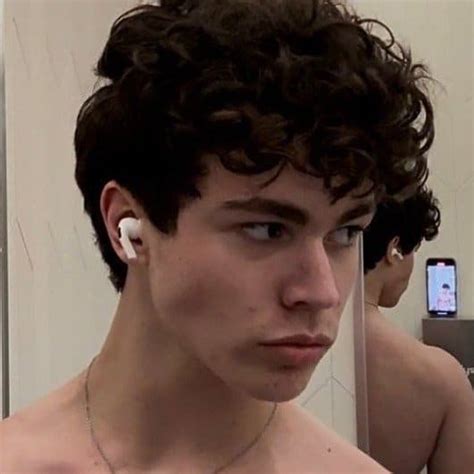a shirtless young man with ear buds on his ears looking at the camera ...