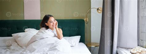 Beautiful sleepy asian girl wakes up in her bed with cozy white