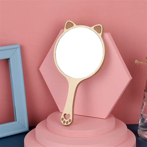 there is a mirror on the table next to a pink vase and blue framed pictures