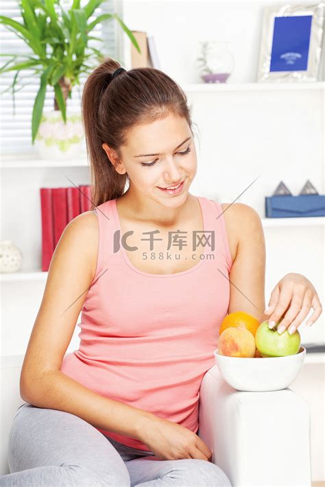家里沙发上拿着水果的快乐女人高清摄影大图-千库网