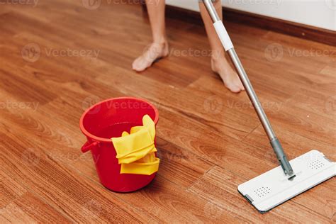 Woman mopping wooden floor with cleaning solution and bucket. red