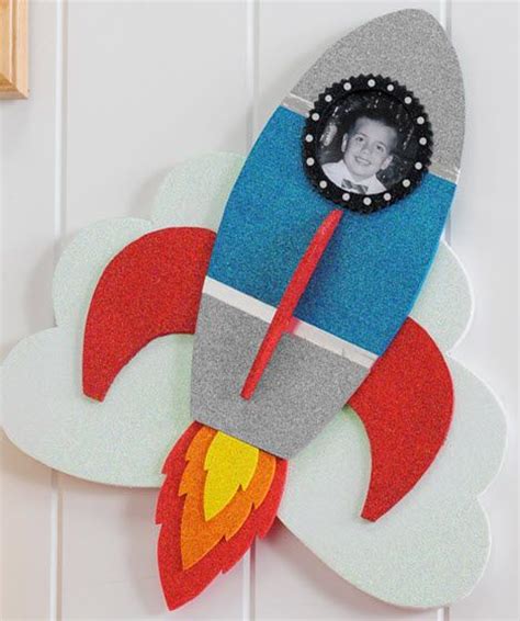 a wall hanging with a rocket ship on it's side and a photo in the center