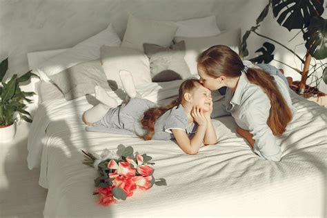 Happy mother kissing daughter in bedroom · Free Stock Photo