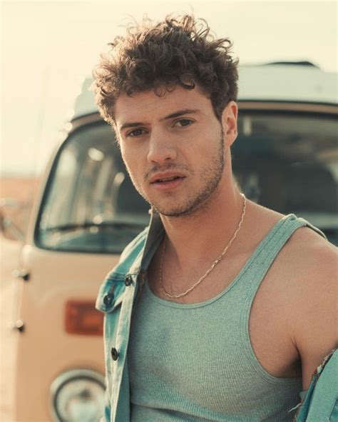a man standing in front of a car wearing a green tank top and silver ...