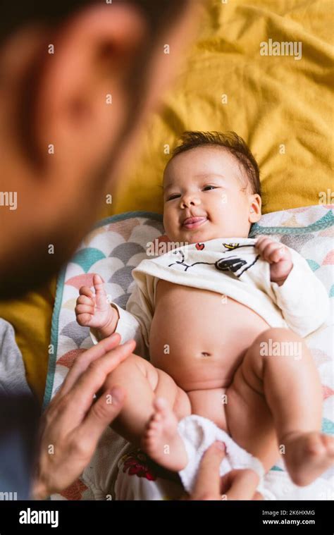 vertical shot of baby during diaper change by young father in bed ...