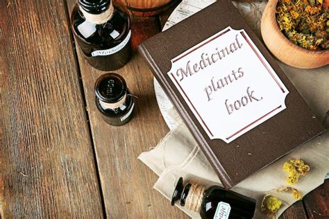 Premium Photo | Medicinal plants book with dried herbs and bottles on ...
