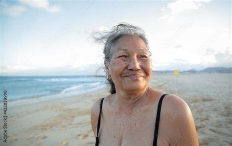 Beautiful senior woman standing at the beach, wearing a black bikini