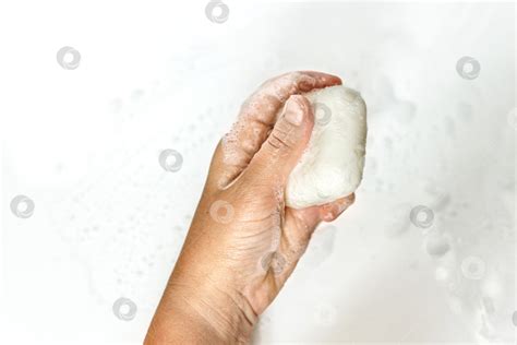 Крупный план рук молодой женщины с куском мыла ручной работы на белом ...