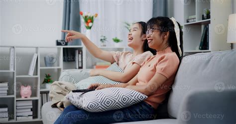 Asian mother and daughter enjoy watch TV together on the sofa at home