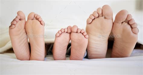 Shot of a family laying barefoot on a bed at home Stock Photo by YuriArcursPeopleimages