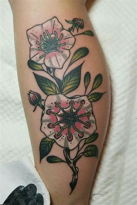 a close up of a person's leg with tattoos on it and flowers in the center