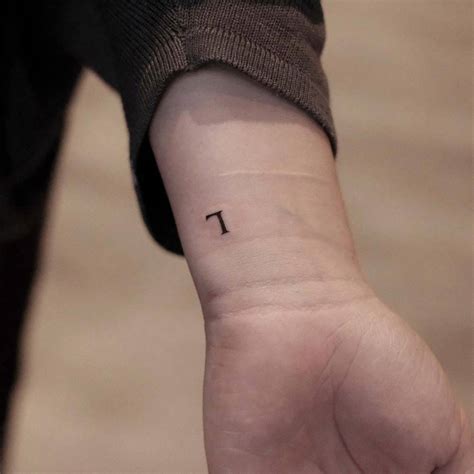 Minimalistic letter "L" tattoo located on the wrist.