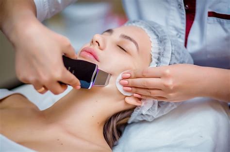Женщина получает ультразвуковой пилинг для лица в косметологическом ...