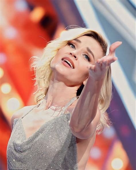 a woman in a silver dress holding her hand up to the side while ...
