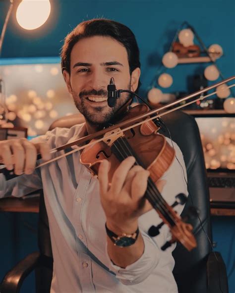 a man holding a violin in his right hand and smiling at the camera ...