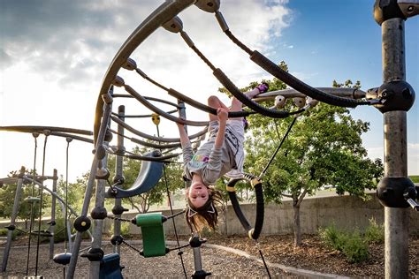 Young Girl Hangs Upside Down At Playground Photograph by Cavan Images