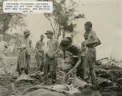 Six emaciated Japanese prisoners of war are overseen by an MP at