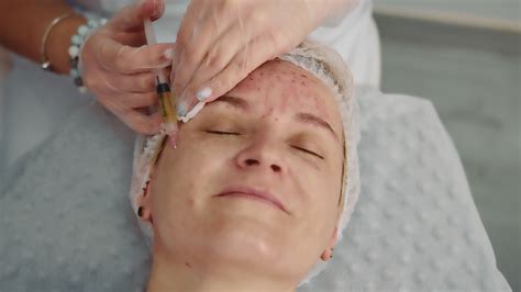 The doctor makes injections of blood plasma into the face of a female