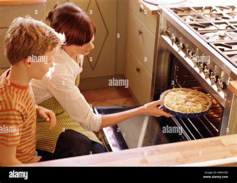 Woman putting pie in oven, child watching Stock Photo - Alamy