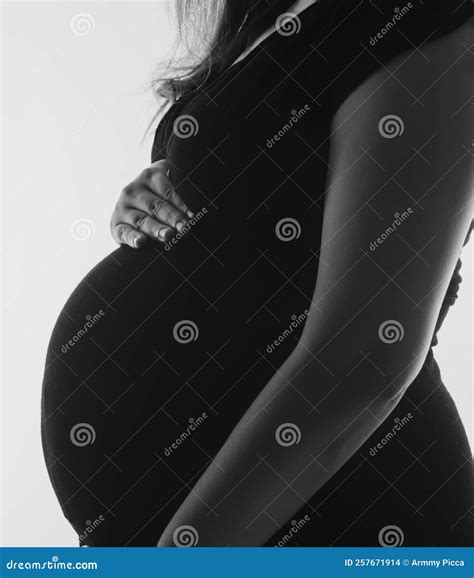 Young Adult Pregnant Woman in White Clothes Touching Big Naked Belly