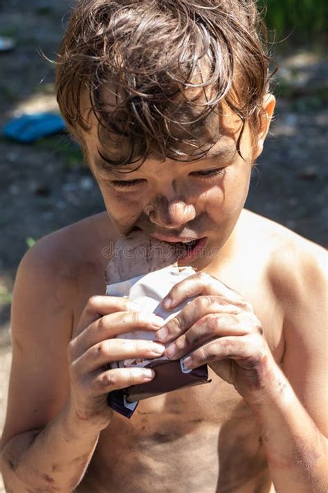 Menino De 9 Anos Pelado E Sujo Morde Uma Barra De Chocolate Coloca