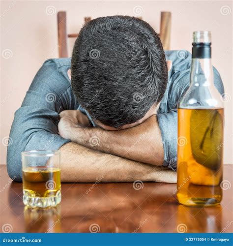 Drunk Man Sleeping with a Whisky Bottle on His Table Stock Photo